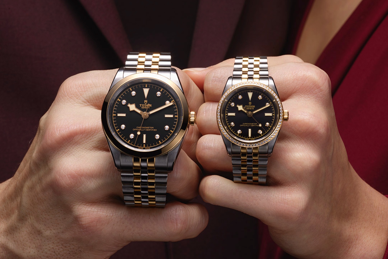 A man and woman holding Black Bay One watches in the men’s and women’s collections by TUDOR