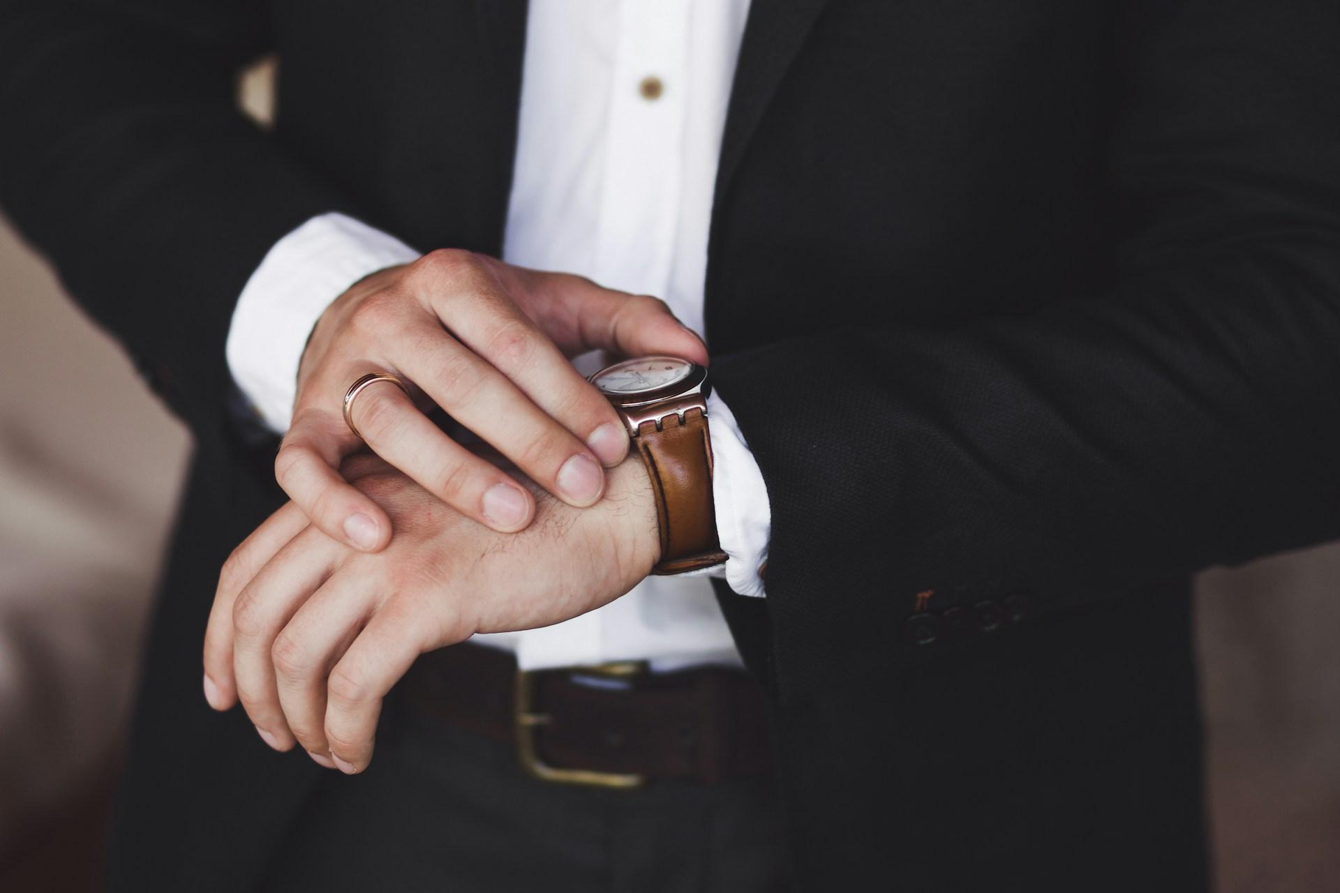 a man checking with watch – a silver case with a brown leather strap