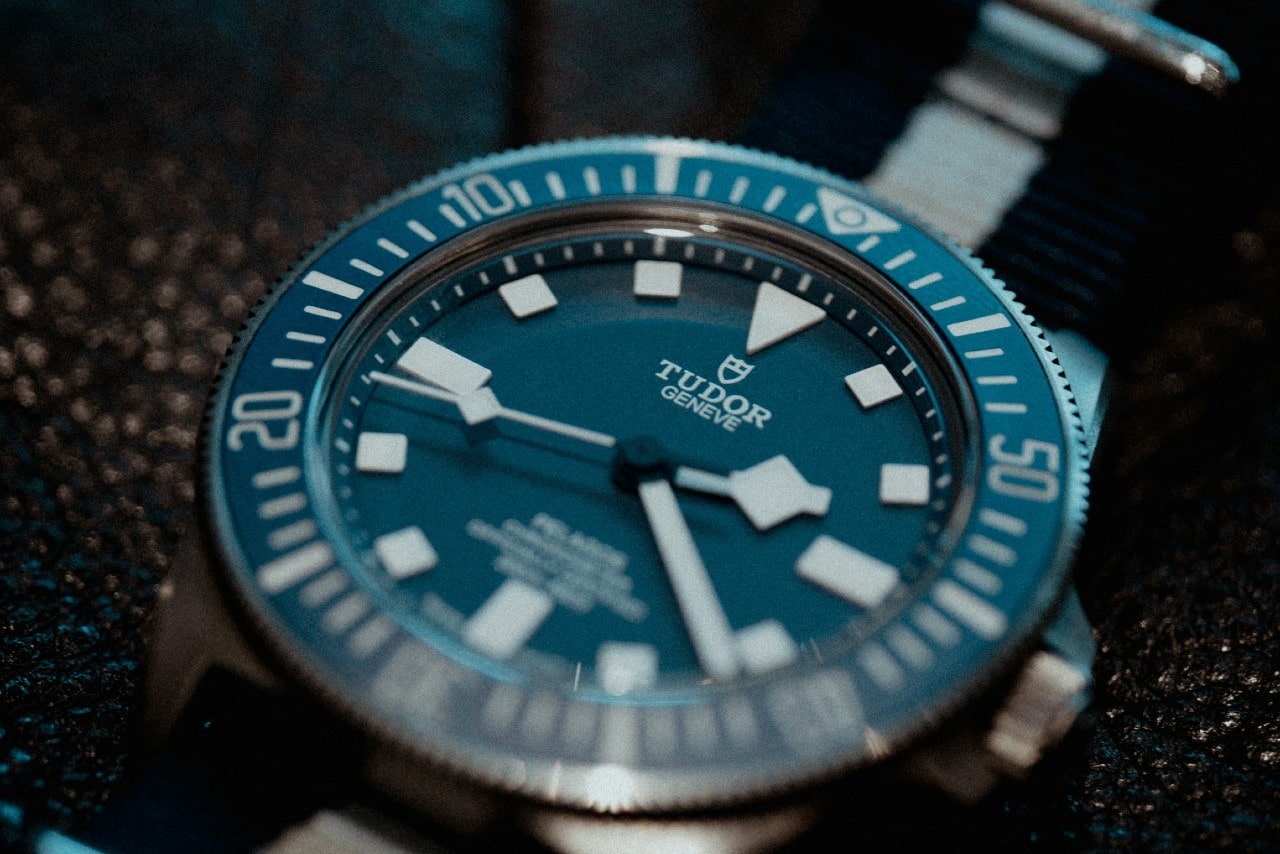 A close-up image of a TUDOR watch with a blue dial and geometric indices