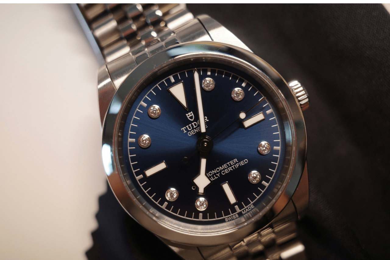 A close-up image of a silver and blue TUDOR watch with diamond indices