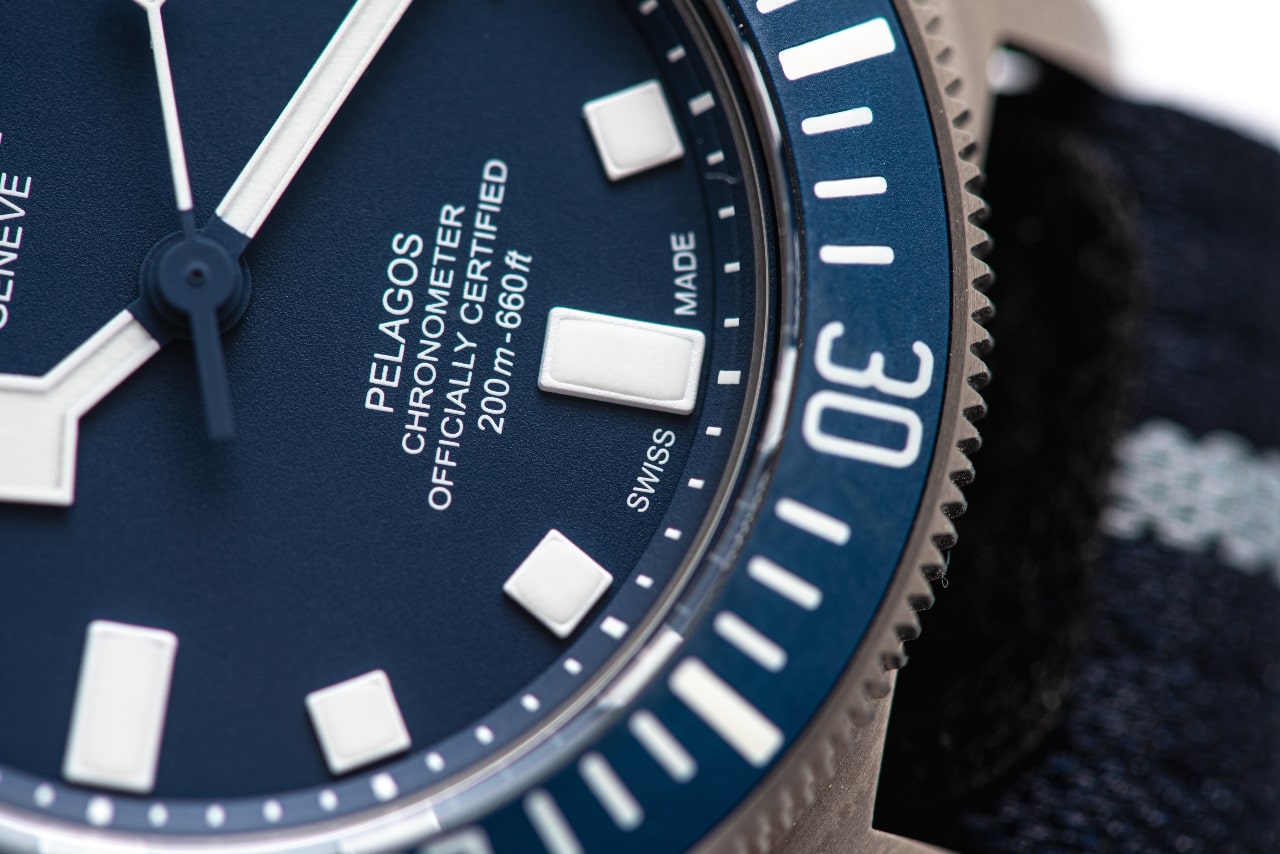 Close up of a TUDOR Pelagos watch with a navy blue dial and bezel with white indexes to match the navy blue and white nylon strap