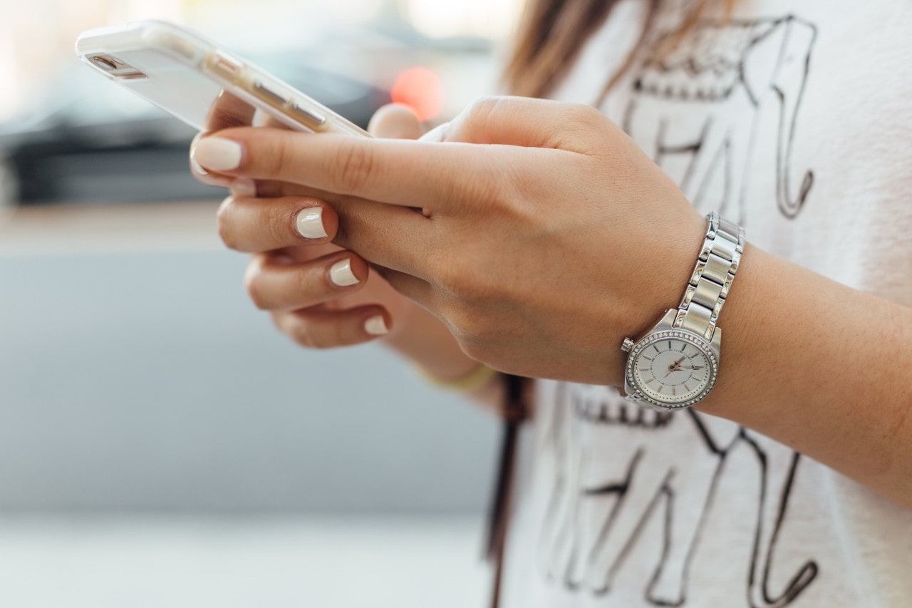 A close-up of a woman’s hands as she uses her smartphone, a stainless steel designer dress watch is on her wrist. A close-up of a woman’s hands as she uses her smartphone, a stainless steel designer dress watch is on her wrist.